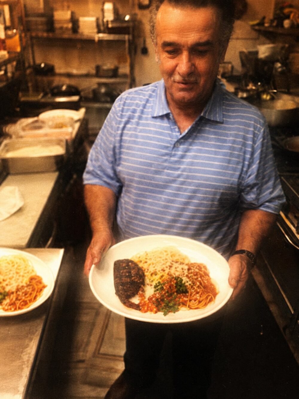 Ray in his kitchen holding a plate of pasta
